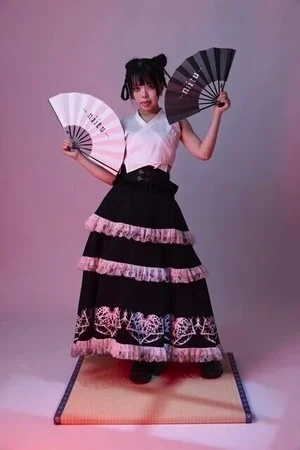 白いトップスに、ピンクのフリルと模様を入れた黒の三段スカートを合わせたステージ衣装