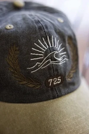 太陽と波の刺繍と「725」のワッペンを付けたキャップ