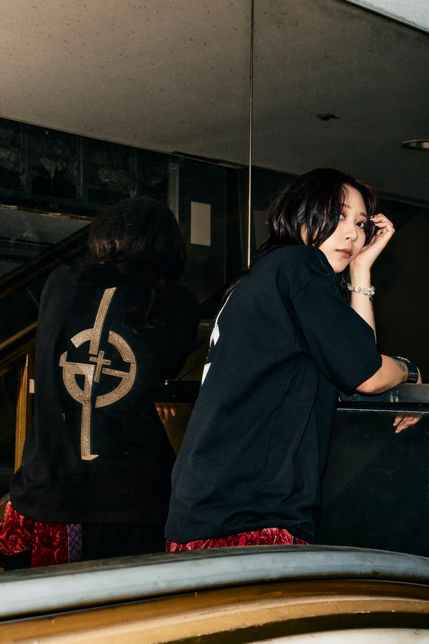 大きな鏡の前に立つ黒いTシャツを着た女性