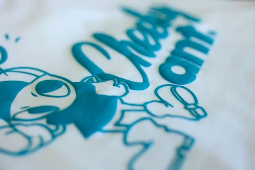 パフ加工されたターコイズ色のロゴTシャツ