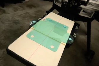 プリントされるケースがスクリーンプリント機のパレットに置かれている