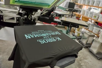 「GSIクレオス ステラターコイズ」と同じ色でプリントされた黒いTシャツ