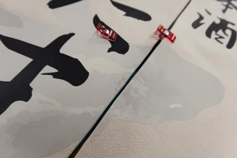 暖簾生地にプリントされたロゴの境界線を赤いクリップで仮止めして位置合わせをしている