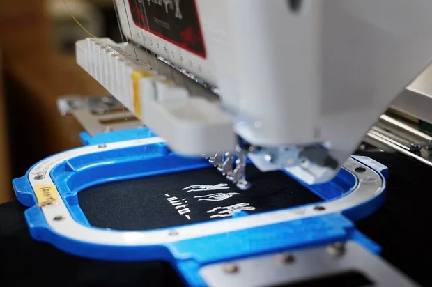 Factory antにある刺繍専用ミシンで白いロゴを加工されている黒いパーカー