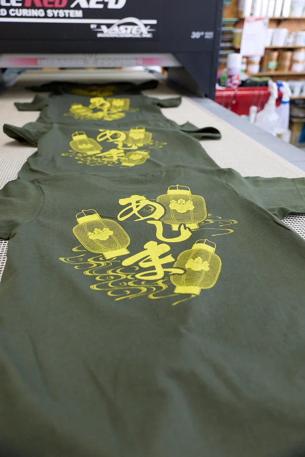 乾燥機から出てきた、黄色いちょうちんの絵をプリントしたカーキのTシャツ