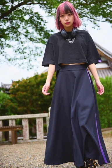 神社の境内に立つモデル。紫のラインが入った黒のロングスカート