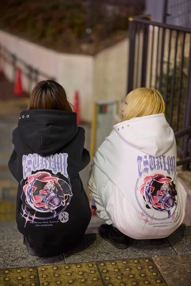 夜の階段にしゃがむ2人の後ろ姿。黒と白のパーカーの背面に同じ絵柄がプリントされている