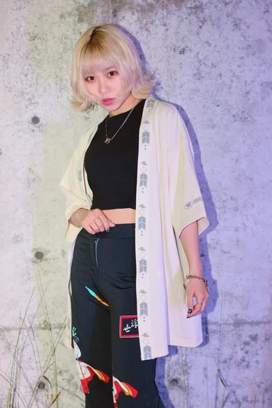 コンクリートの壁の前に立つモデル。前立てに柄をあしらったオフホワイトの羽織Tシャツ