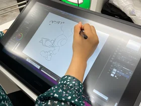 ペンタブレットでアント君のイラストを描いているスタッフ