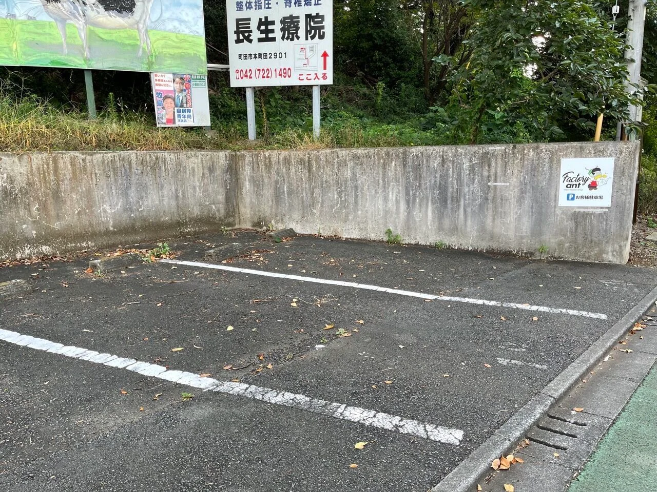 白線で区切られた無料駐車場。壁にアント君の看板が貼ってある