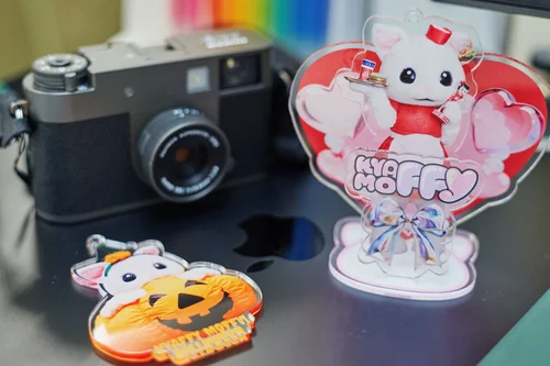 カメラの横に置かれた、ハートの背景にアップちゃんが描かれたKYAFFY MOFFYのアクリルスタンドと、かぼちゃの形のアクリルアイテム