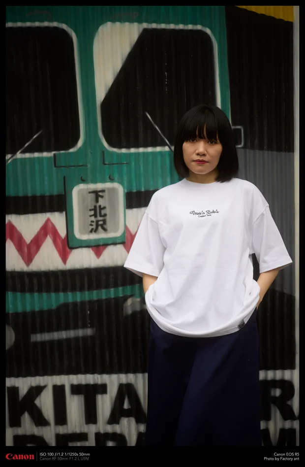 下北沢の壁画の前に立つモデル。Cheeky ant の「That's Sick!」ロゴ入り白Tシャツ