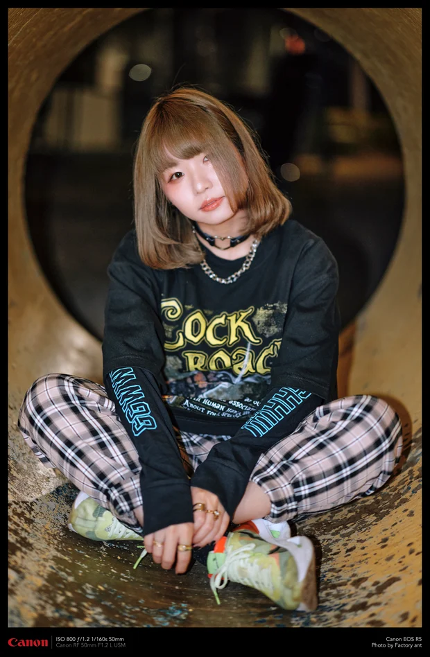 土管の中に座るモデル。Cheeky ant の「COCKROACH」グラフィックの黒ロングスリーブTシャツ
