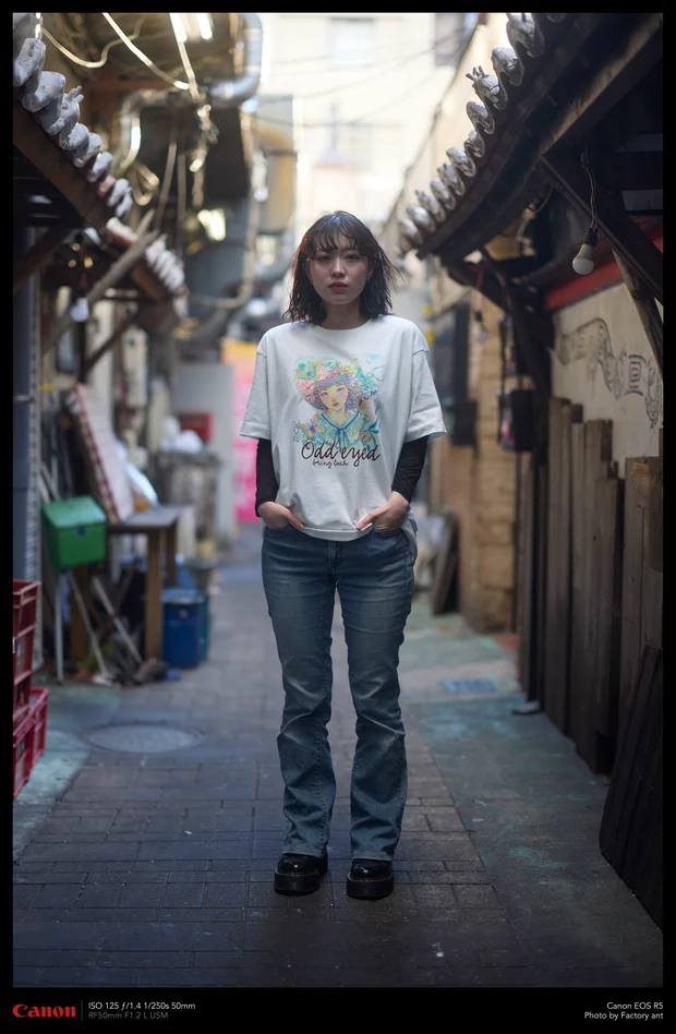 路地に立つモデル。Kawaii Apparel のオッドアイの女の子のイラスト入り白Tシャツ