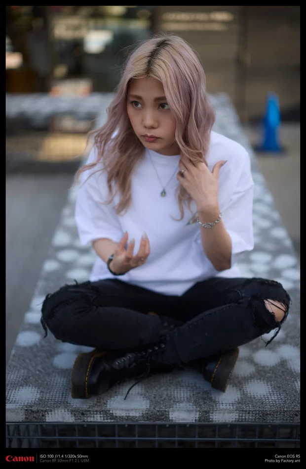 石のベンチにあぐらをかくモデル。Kawaii Apparel の白Tシャツ