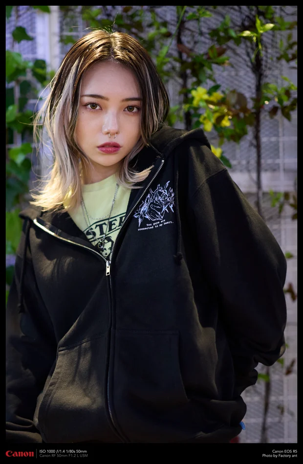 夜の街に馴染んでいるモデル。Kawaii Apparel の黒いジップパーカー