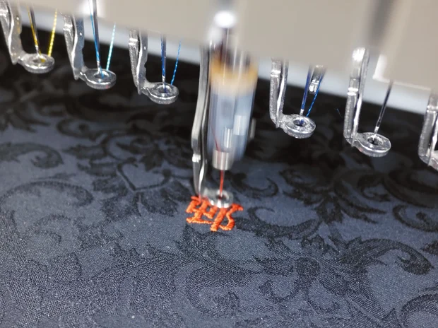黒い生地に鮮やかなオレンジ色の糸で刺繍加工している