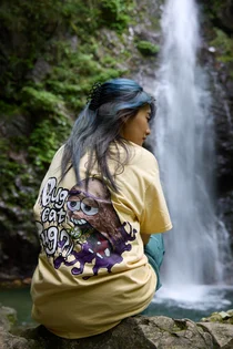 滝の前で、背中にフルカラーのイラストをDTFプリントしたTシャツを着た人