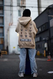 背中に細かなイラストと「ONENESS」の文字をDTFプリントしたベージュのパーカー